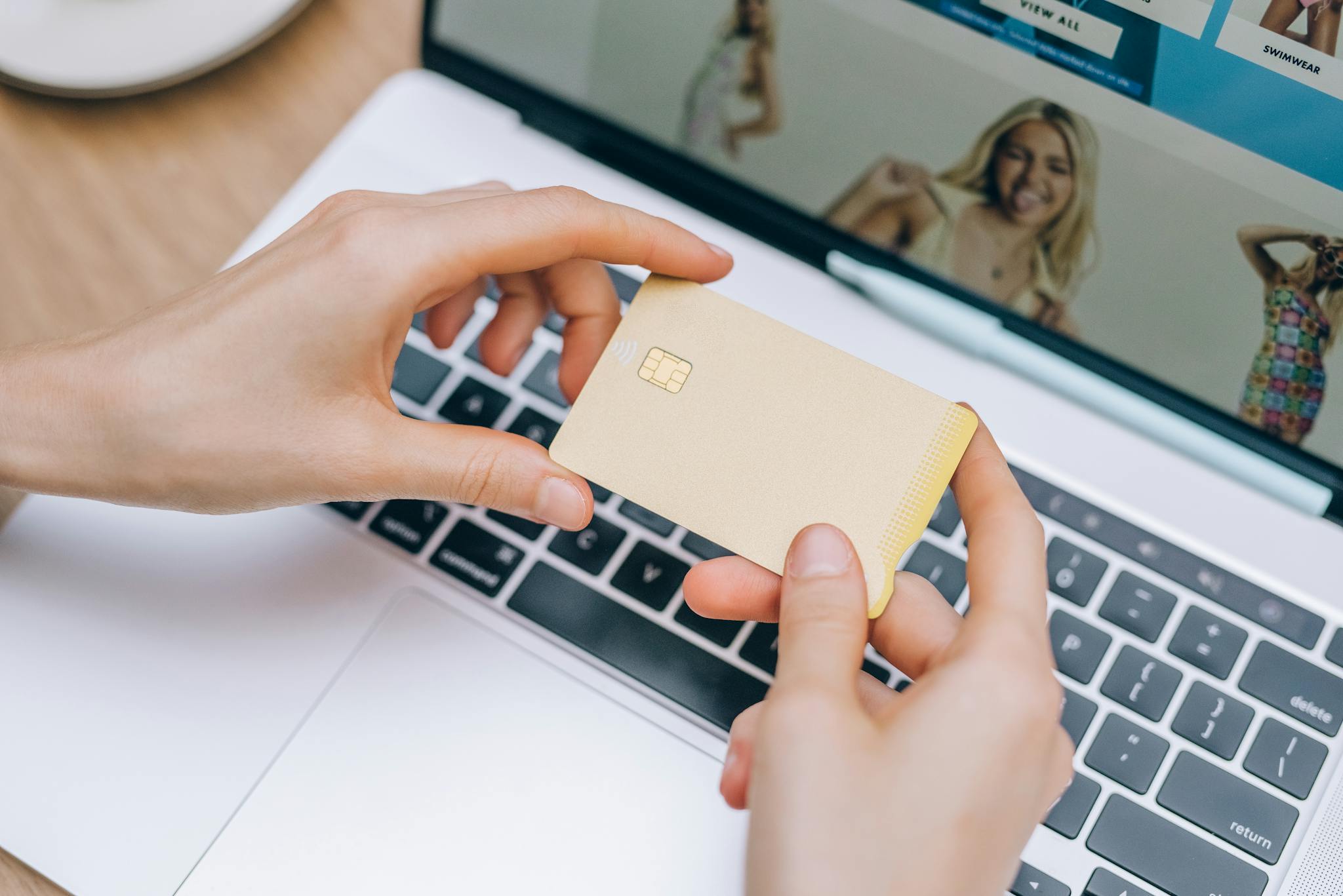 Close-up of hands holding credit card for online shopping on a laptop. Perfect for e-commerce and finance visuals.